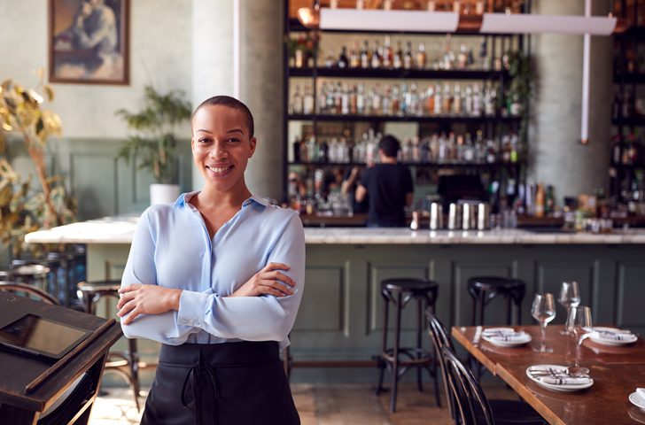 Female business owner standing confidently in front of counter