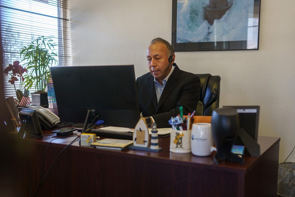 Chris Gutiérrez, cliente de Lendistry y propietario de un negocio, trabajando en su escritorio y hablando por teléfono