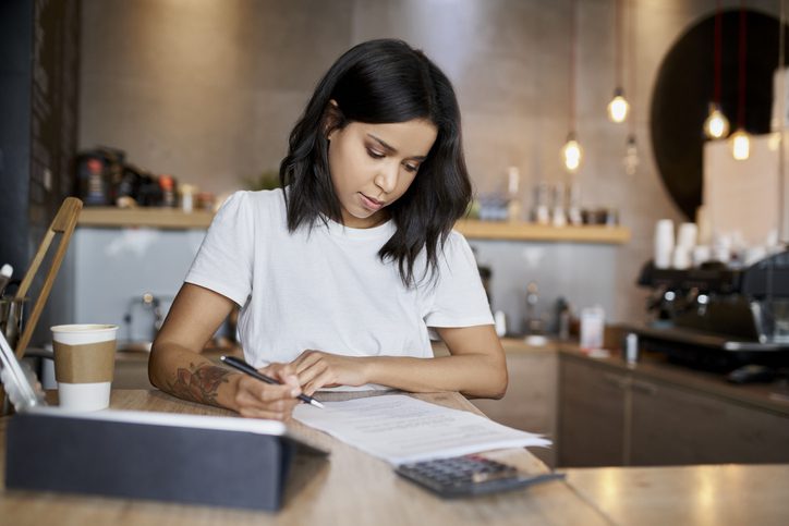 Mujer propietaria de una cafetería mirando el papeleo relativo a un préstamo para una pequeña empresa