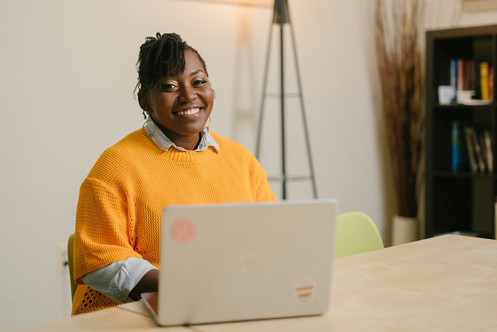 La clienta de Lendistry Jaree Cottman, de AFYA Counseling and Wellness, sonríe con su portátil en su oficina