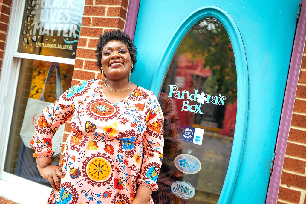 Lendistry customer and small business owner Monesha Phillips of Pandora's box smiles happily in front of her shop in Baltimore