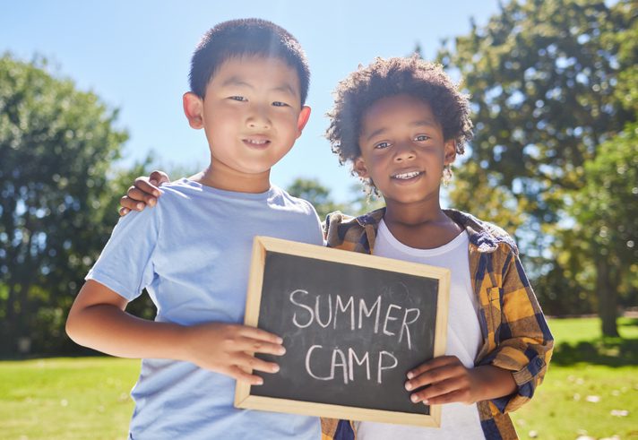 2 young kids holding a sign that says summer camp