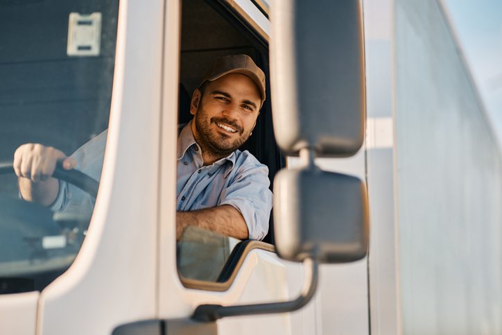 El feliz propietario de un negocio de camiones mirando por la ventana y planeando solicitar un préstamo para ampliar su negocio