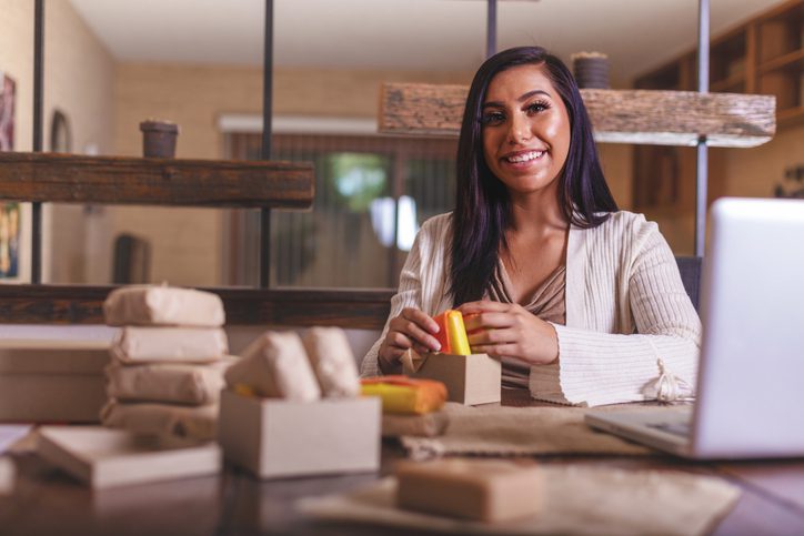 Native American Small business owner smiling while wrapping and package