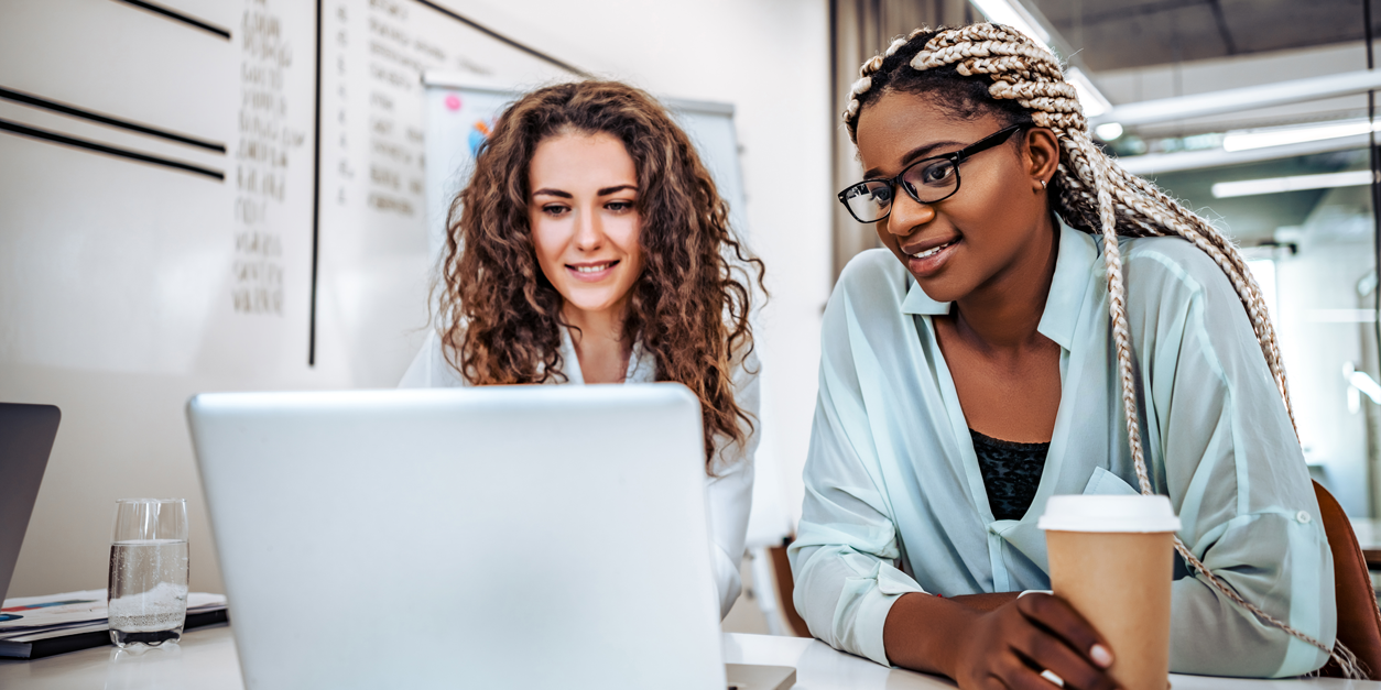 Joyful young business women looking at laptop screen while rest from work.