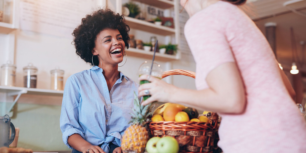 Juice bar owner talking to female customer.