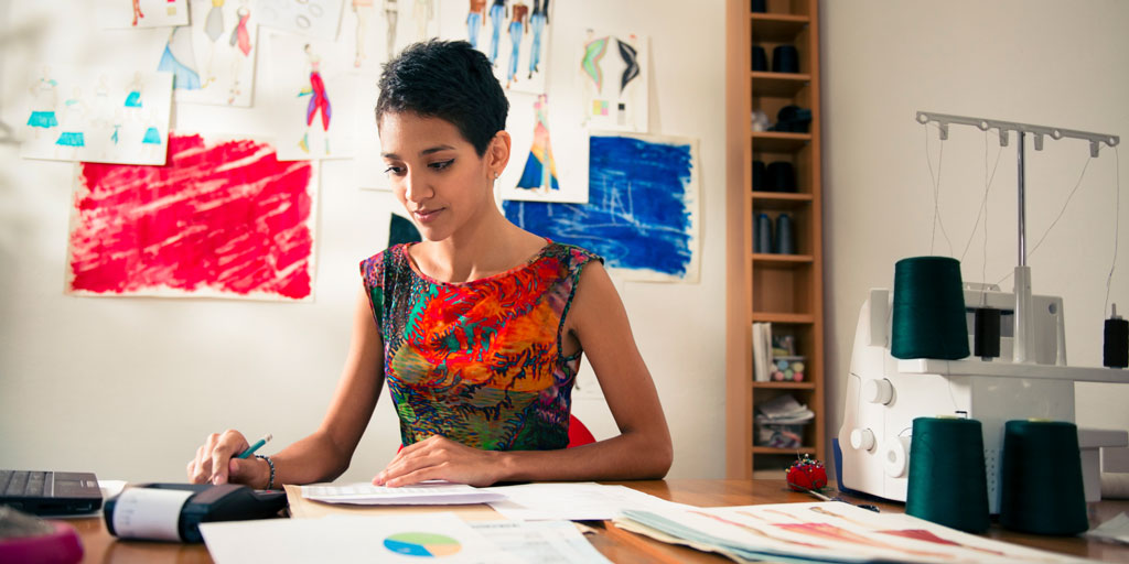 Hispanic woman doing budget in fashion designer atelier