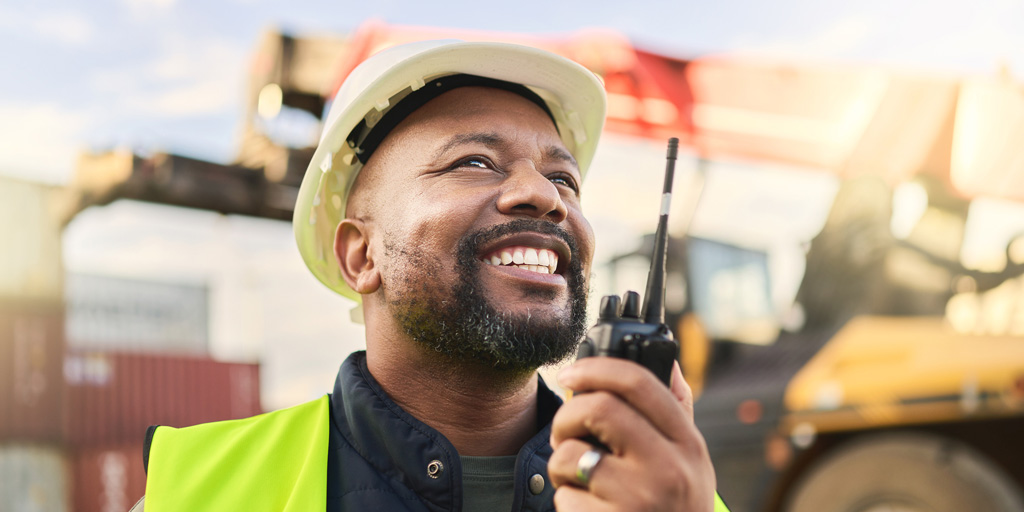 Man using radio communication, shipping logistics and supply chain management to organize inventory. Freight cargo stock, commercial container for exports and import storage at a shipyard warehouse