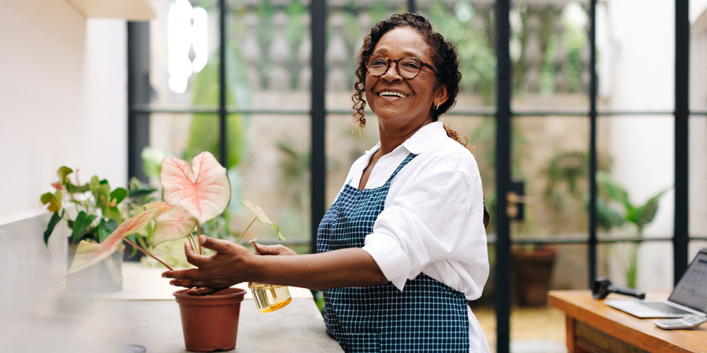 Cheerful flower arranger taking care of a plant in her shop