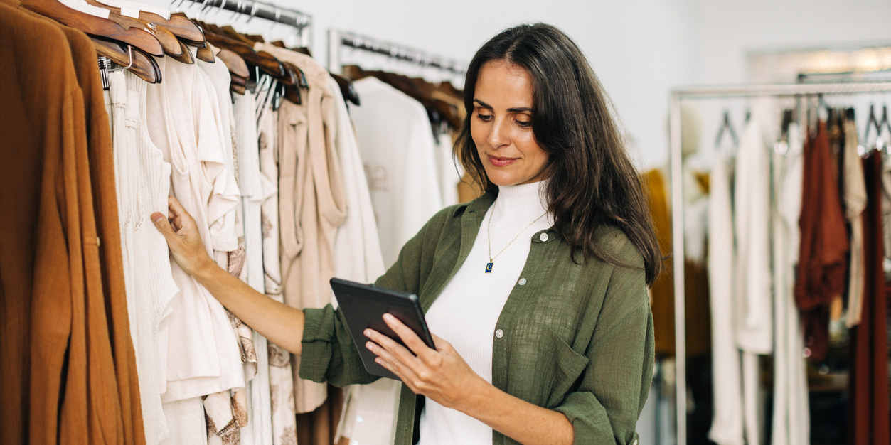 Woman holding tablet checking inventory of clothes