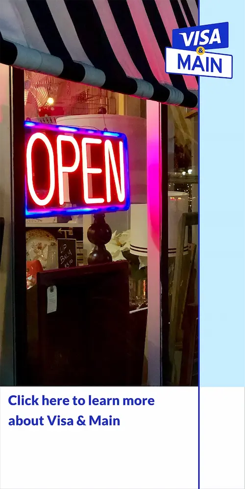 Store front with neon OPEN sign brightly displayed at night with VISA & Main logo placed in the top right corner and Click here to learn more about Visa & Main link below