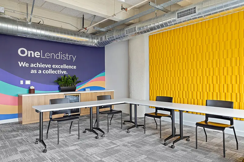 Lendistry LA office training room with yellow textured design on one wall and One Lendistry - We achieve excellence as a collective tagline on the other wall with a colorful ribbon flowing design below