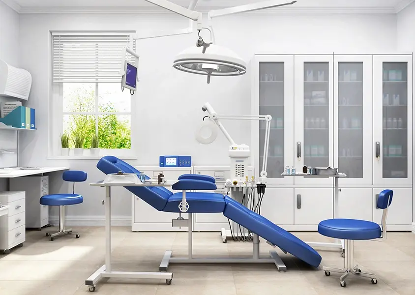 Interior of a modern dental clinic with a blue patient chair and dental equipment and cabinets in the background