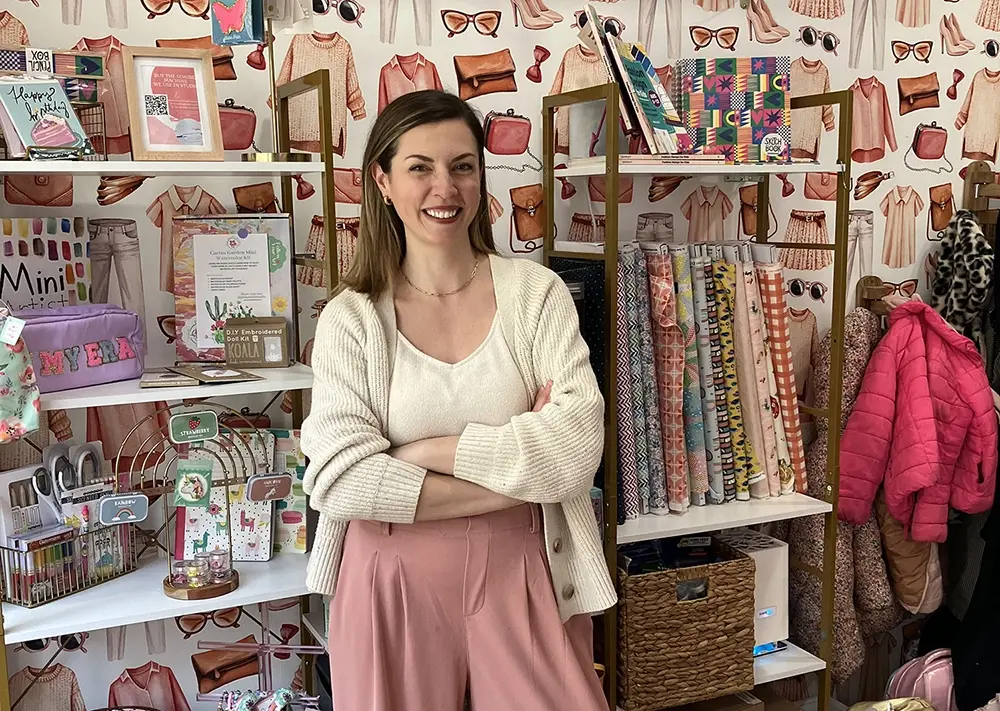 Kerri Quigley of The Fashion Class standing in her store posing for the camera with arms crossed and smiling